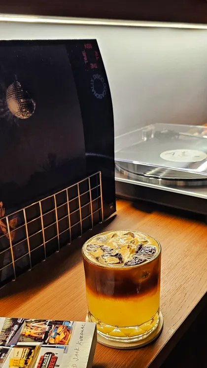 A layered iced coffee beside a record player at Juno Coffee Club